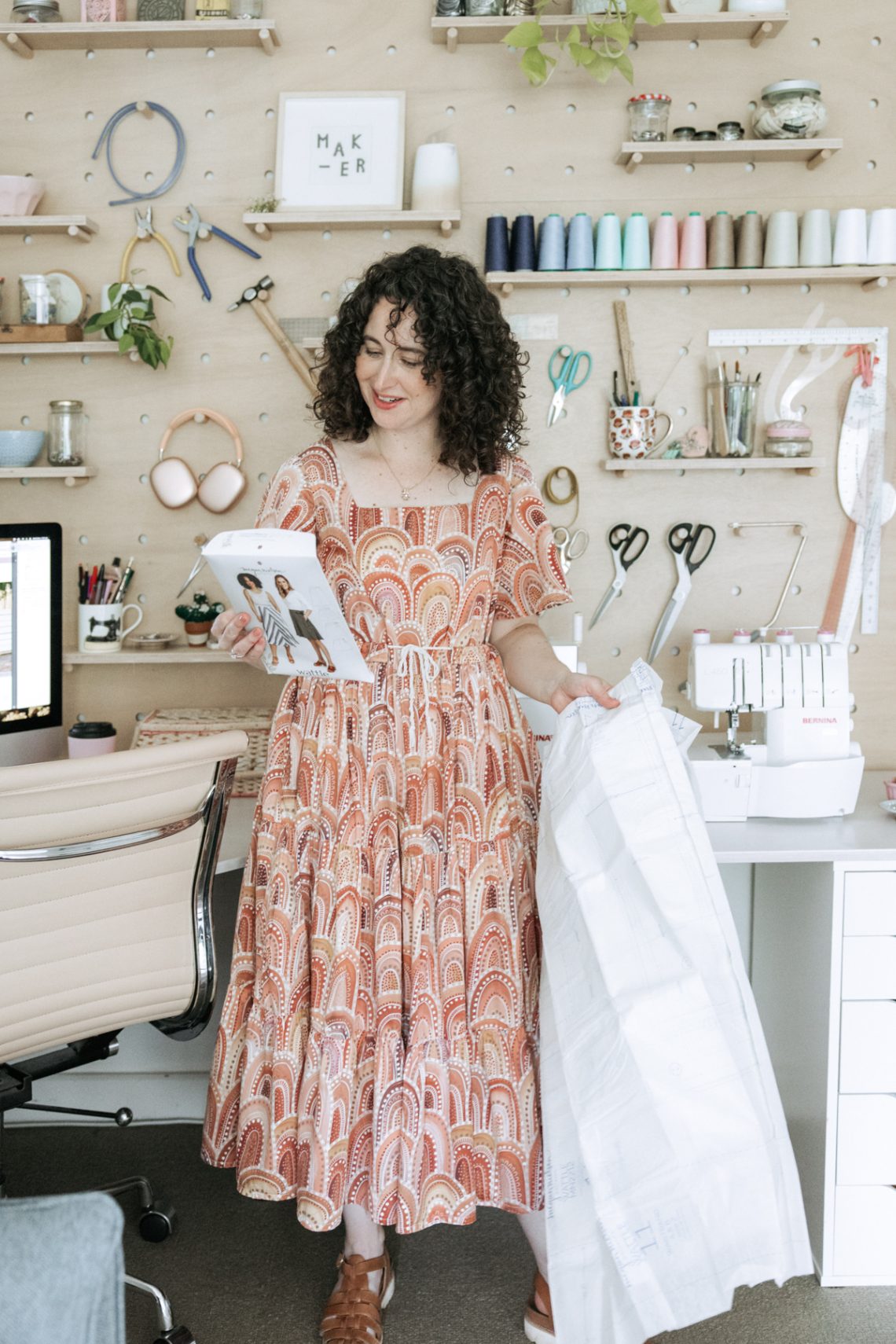 Megan Nielsen in her workroom. Wearing the Protea dress in front of her plywood pegboard wall